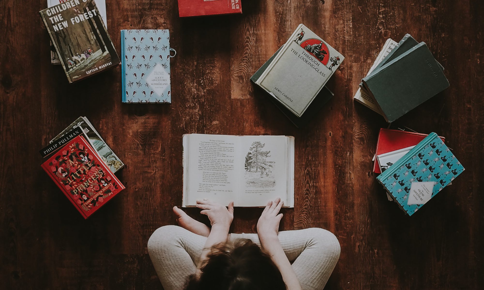 photo of a child surrounded by piles of books to advertise the santa Clara city library foundation and friends' October 2019 book sale